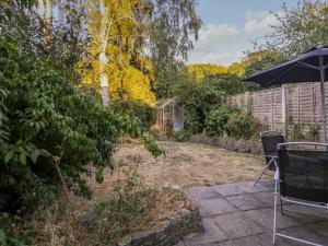 un jardín con sombrilla y un patio con invernadero en The Perch, en Bexley