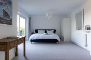 a white bedroom with a bed and a desk at Furzedown Farm House in Hythe
