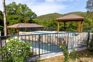 una piscina con un pabellón y un cenador en Karucoco lodge, en Deshaies