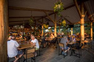 a group of people sitting at tables in a restaurant at Lake Shkodra Resort in Grilë