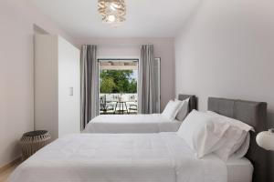 una camera da letto bianca con due letti e una finestra di Villa Maria Rose a Kassiopi Altre 35 foto