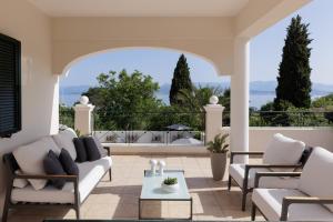 un soggiorno con divano e sedie su un patio di Villa Maria Rose a Kassiopi