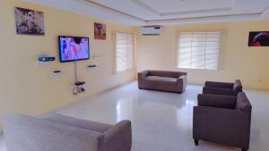 a living room with two chairs and a couch and a tv at Abuja Modern Apartments in Abuja