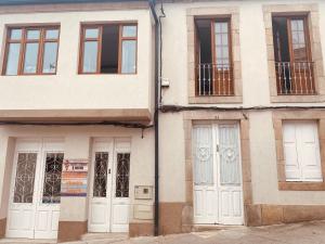 un edificio con puertas y ventanas blancas en una calle en Albergue y Gelateria il nonno en Sarria