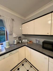 a kitchen with white cabinets and a microwave at Charming 3 bed Bungalow in Bromley