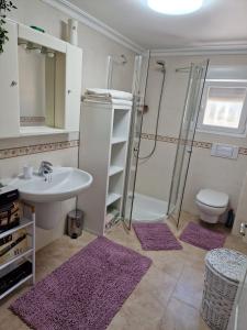 ein Badezimmer mit einem Waschbecken, einer Dusche und lila Teppichen in der Unterkunft Carrio appartement 2 chambres in Calpe