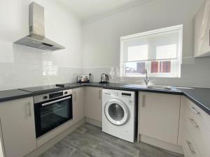 a white kitchen with a washing machine and a sink at Stanhope Road in South Shields
