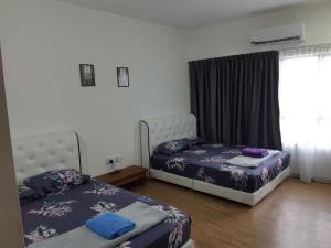 a bedroom with two beds and a window at UMMI GUESTROOM in Kota Bharu