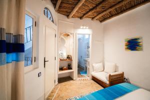 een slaapkamer met een bed en een stoel in een kamer bij Dar Liouba Hotel in Essaouira