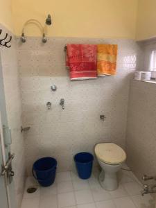 a bathroom with a toilet and two blue buckets at Jamna vilas Home Stay in Bikaner
