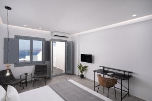een slaapkamer met een bed, een bureau en stoelen bij El Destino Suites in Akrotiri