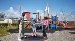 un homme, une femme et une petite fille dans une aire de jeux dans l'établissement Sophie's Caravan, à Camber