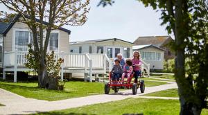 a family riding a toy car in a yard at Sophie's Caravan in Camber
