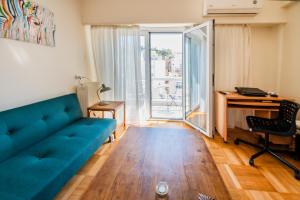 ein Wohnzimmer mit einem blauen Sofa und einem Schreibtisch in der Unterkunft 5th Floor Boho Quircky in Athen