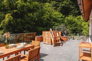 a patio with wooden tables and chairs and trees at Loughrigg Cottage in Ambleside