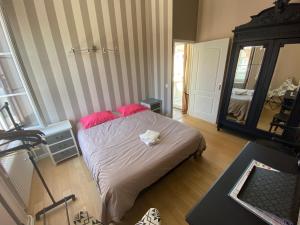 - une chambre avec un lit doté d'oreillers roses et d'un miroir dans l'établissement Maison de ville au cœur de Saint Pierre en Auge, à Saint-Pierre-sur-Dives