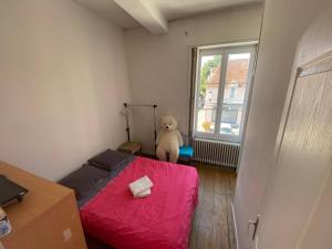 - une petite chambre avec un lit rouge et un ours en peluche dans l'établissement Maison de ville au cœur de Saint Pierre en Auge, à Saint-Pierre-sur-Dives