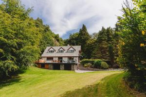 una grande casa su una collina erbosa con alberi di Loughrigg Cottage ad Ambleside