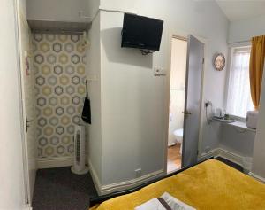 ブラックプールにあるHornby Villa 4*B&B Couples & Families Onlyのベッド1台と壁掛けテレビが備わる客室です。
