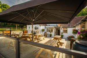 an umbrella on a patio with tables and benches at The White Lion, Soberton in Soberton