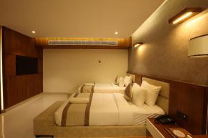 a hotel room with two beds and a television at Royal Plaza Suites in Mangalore