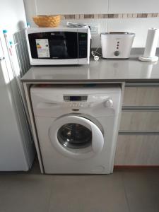 a microwave sitting on top of a washing machine in a kitchen at Departamento luminoso PB in San Martín de los Andes