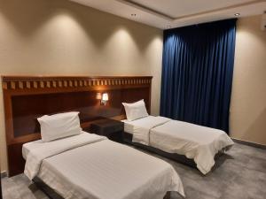 a hotel room with two beds and a blue curtain at شقق درر رامه للشقق المخدومة 11 in Riyadh