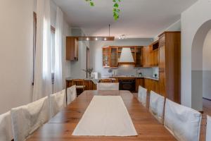una cucina e un lungo tavolo da pranzo con sedie. di Villa Rosè - Natura vista mare - Narramondo Villas a Cologna