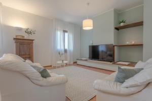 uma sala de estar com um sofá branco e uma televisão em Villa Rosè - Natura vista mare - Narramondo Villas em Cologna