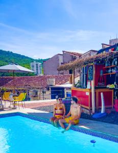 dos personas sentadas en el borde de una piscina en Trip Monkey Hostel en San Gil