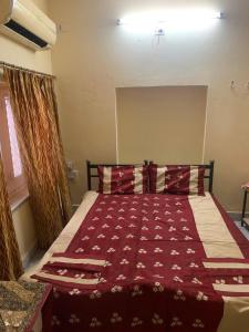 a bedroom with a bed with a red comforter at Jamna vilas Home Stay in Bikaner