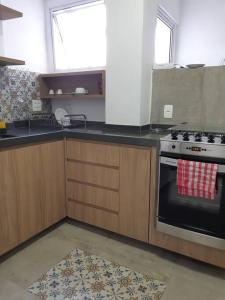 uma cozinha com armários de madeira e um forno com placa de fogão em Varanda_77 em São Paulo