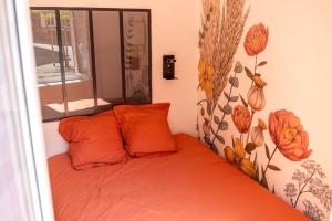 a bed with orange pillows in a room with a window at Appartement Cosy avec Jardin au Centre Historique de Sélestat & Proche Europa-Park in Sélestat
