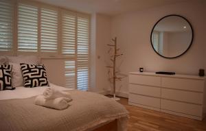 een slaapkamer met een bed met een spiegel en een dressoir bij Les Dunes in Camber