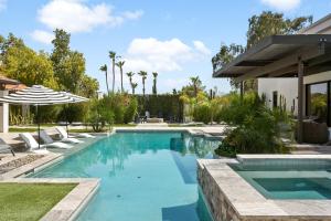 a swimming pool with chairs and an umbrella at ModernCompound in Scottsdale
