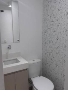 uma casa de banho com um WC branco e um lavatório. em Varanda_77 em São Paulo