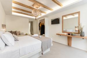 a white bedroom with a large bed and a mirror at Heavenly Suites & Studios in Naxos Chora