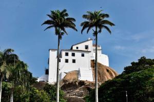 a white building on top of a hill with palm trees at Residencial Pasárgada, apto 602 in Vila Velha
