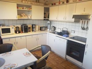 una cucina con mobili bianchi e un tavolo con sedie di Entspannen & Wohlfühlen in der Lüneburger Heide a Vierhöfen