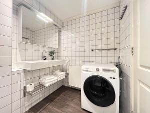 een wit betegelde badkamer met een wasmachine bij Apartment Eewal 68 in Leeuwarden