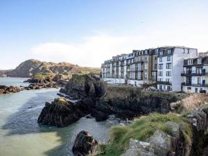 a building on a cliff next to a body of water at No 5 Compass - Ilfracombe in Ilfracombe