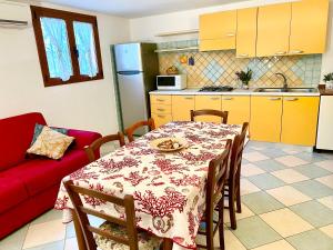 uma cozinha e sala de jantar com uma mesa e um sofá vermelho em Appartamento Le Ginestre em Monte Nai