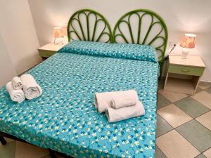 um quarto com uma cama azul com toalhas em Appartamento Le Ginestre em Monte Nai