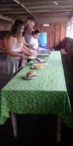 eine Gruppe von Menschen, die um einen langen Tisch mit Teller Essen stehen in der Unterkunft Golden waters Lodges in Iquitos