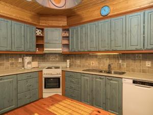 Il comprend une cuisine avec des placards verts et un plafond en bois. dans l'établissement Holiday Home Kinostupa 2a - 18 by Interhome, à Ruka