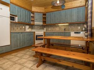 kuchnia z niebieskimi szafkami oraz stołem i ławkami w obiekcie Holiday Home Kinostupa 2a - 18 by Interhome w mieście Ruka
