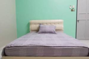 een bed in een slaapkamer met een blauwe muur bij Mersing Spacious 3bedroom with free parking space in Mersing