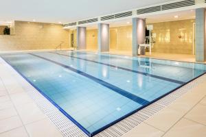 厄科納的住宿－畢當格斯澤特拉姆艾克尼爾酒店，一座位于大楼内的游泳池,铺有蓝色的瓷砖地板