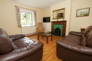 a living room with a leather couch and a fireplace at Beeches Cottage - Beautiful Garden - Parking in Handcross