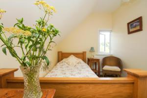 a vase with flowers on a table in a bedroom at Beeches Cottage - Beautiful Garden - Parking in Handcross